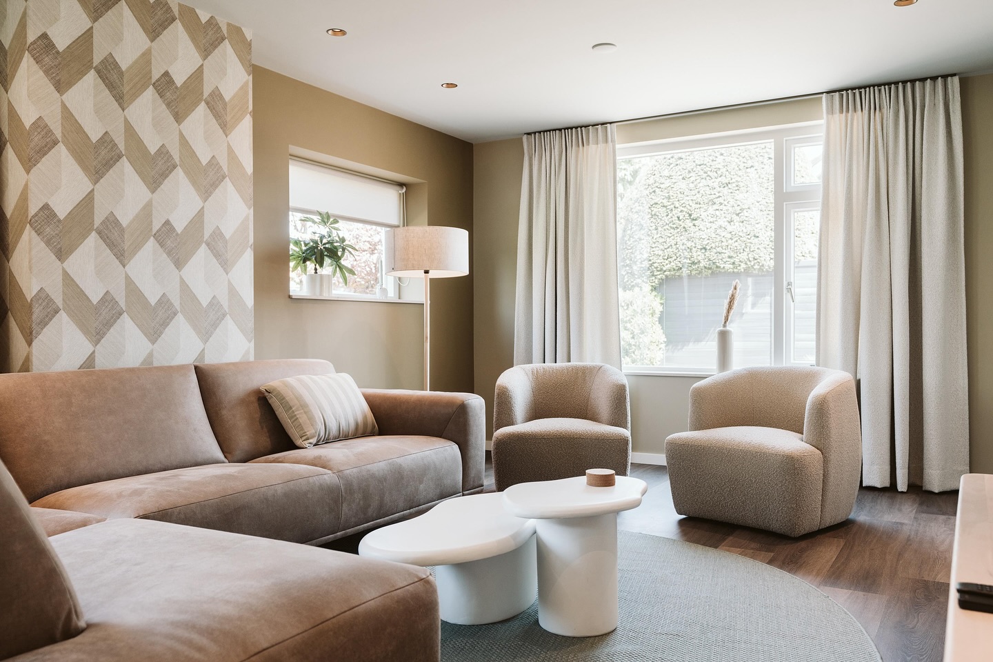 Afgewerkte woonkamer met beige wanden en een wand met chevronbehang