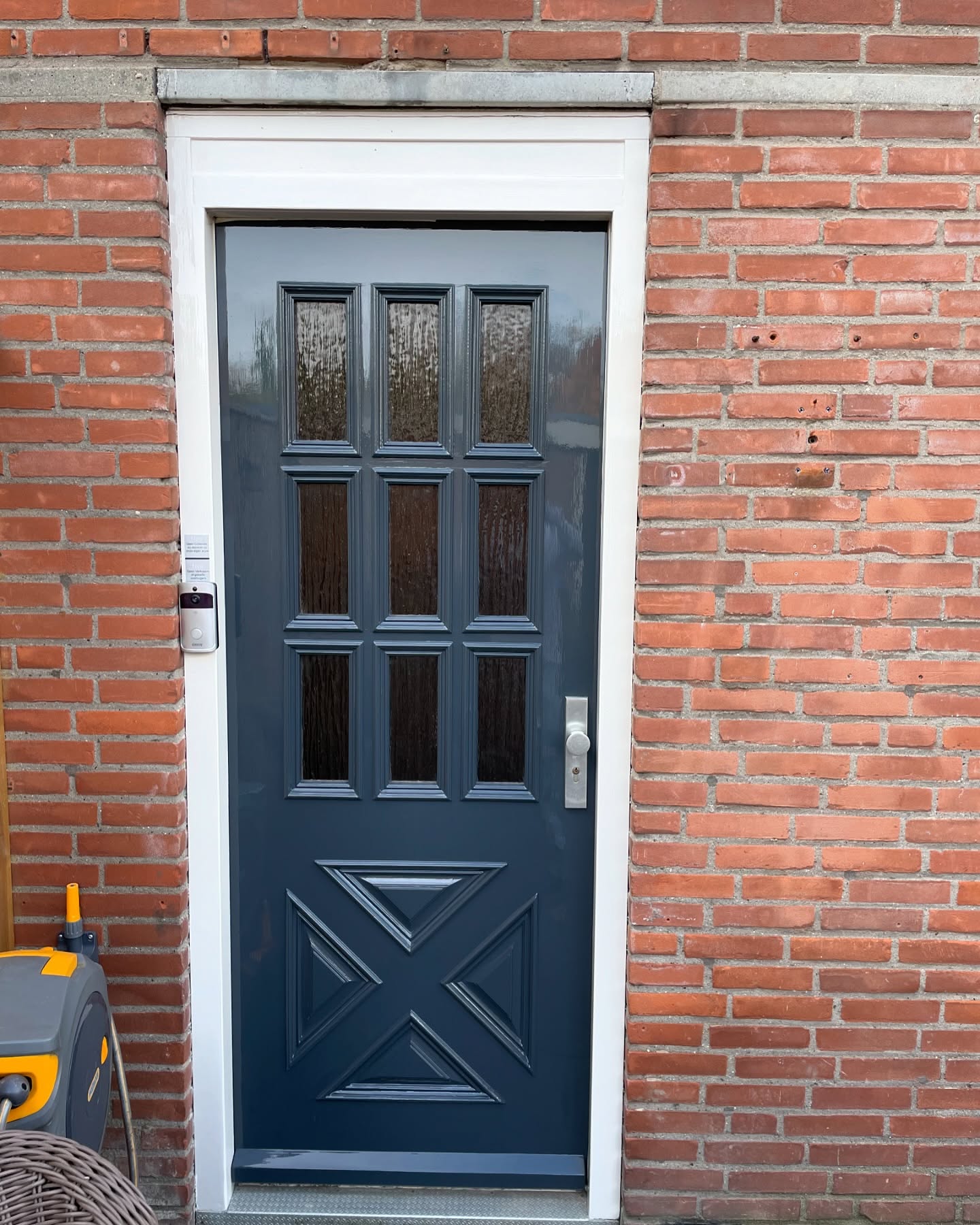 Donkerblauw geschilderde voordeur met glas in een rode bakstenen gevel