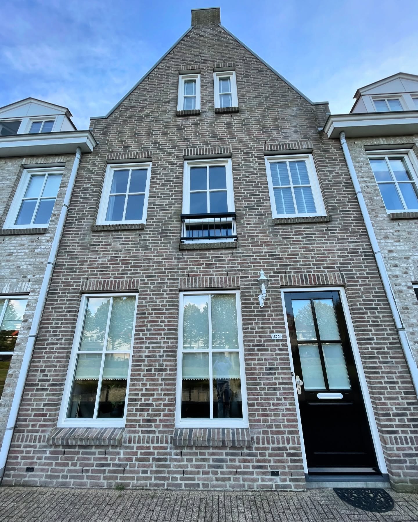 Bakstenen gevel met fris geschilderde witte kozijnen en een zwarte voordeur